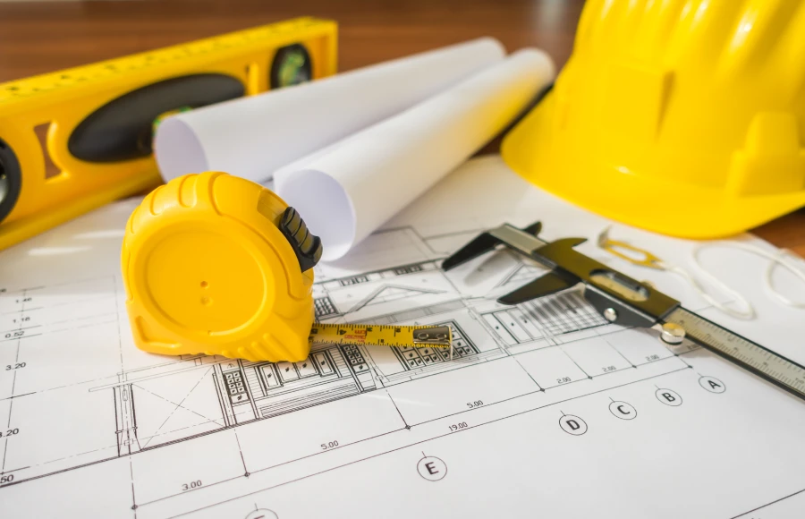 los planes de construccion con casco amarillo y herramientas de dibujo en bluep.webp
